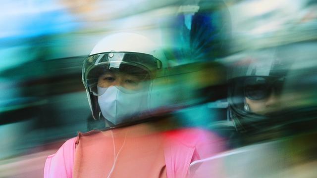 Detail of Taiwanese girl in a white helmet between blurry crowd