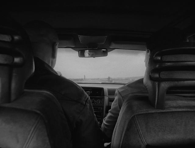 Two men sitting in the front of an old car