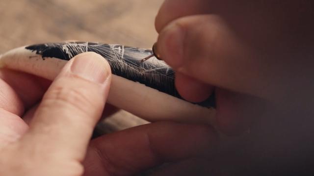 Hand carving an image onto a whale tooth